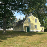 Photo showing a historic yellow house located in a park-like setting