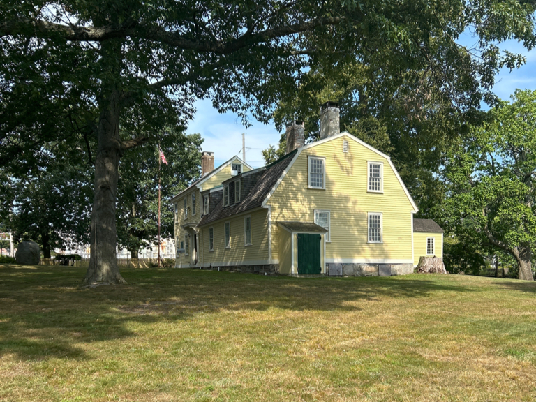 Photo showing a historic yellow house located in a park-like setting