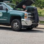 Parks Mechanic under the hood of a 2015 3500 landscape truck on a roadside assistance call