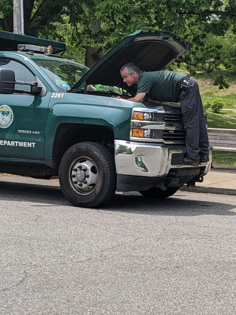 Parks Mechanic under the hood of a 2015 3500 landscape truck on a roadside assistance call