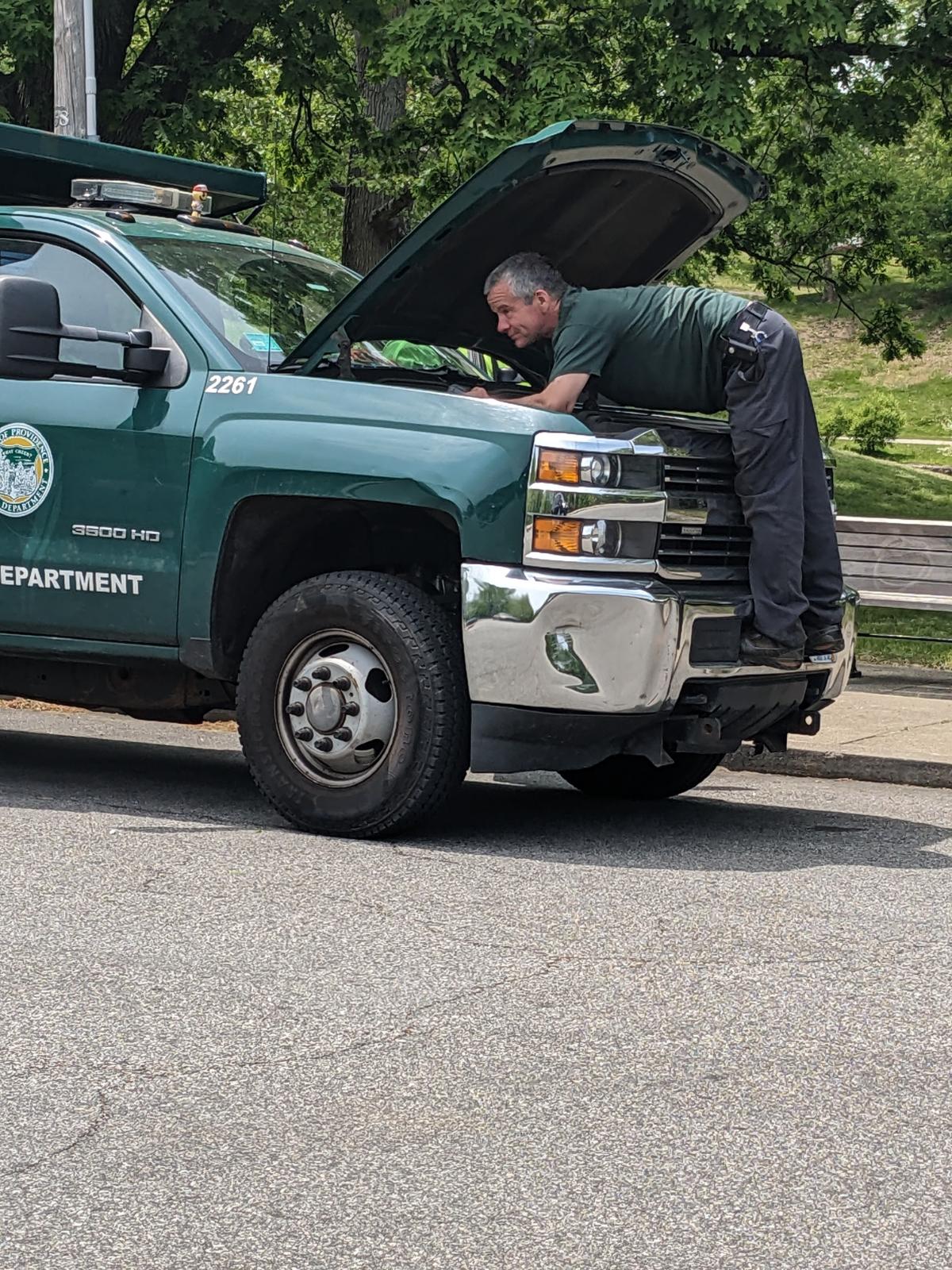 Parks Mechanic under the hood of a 2015 3500 landscape truck on a roadside assistance call