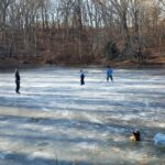 photo of 3 children playing hockey on a frozen pond