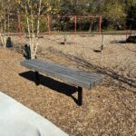 photo showing a park bench with a swingset in the background
