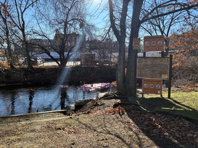 photo of a park warning sign with a stream behind it