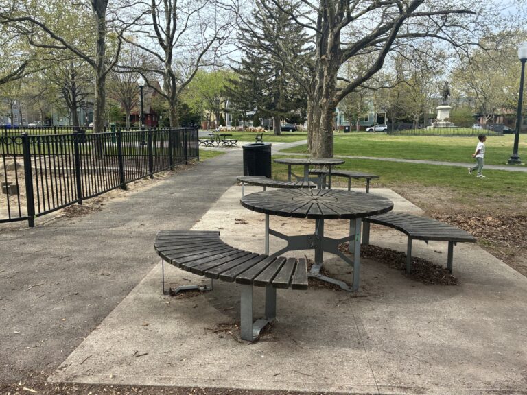 photo showing picnic tables in a providence park and a child playing in the background