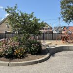 photo showing playground structures and flowering bushes
