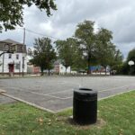 photo of a trash can with a basketball court in the background