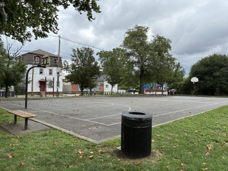 photo of a trash can with a basketball court in the background
