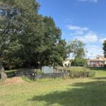 photo showing a community garden area that is surrounded by a fence a grass fields