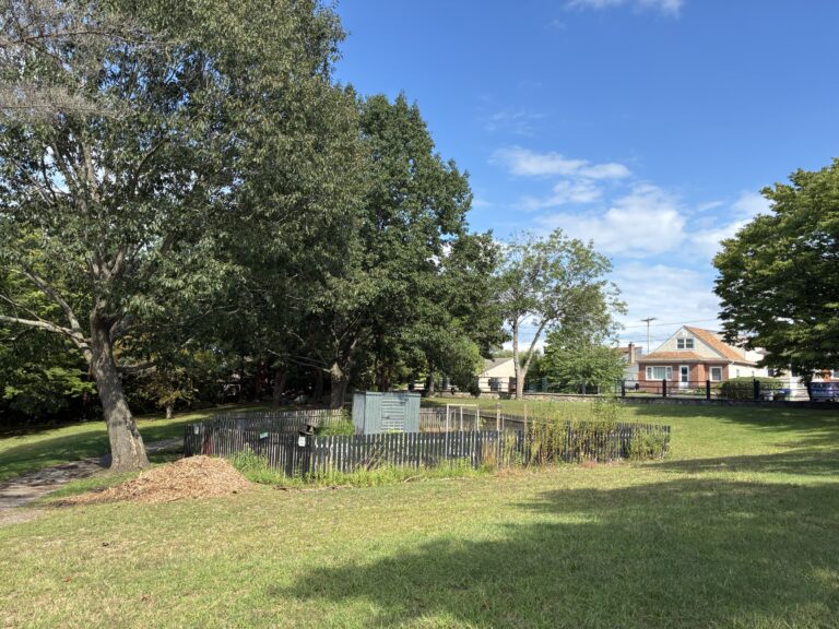 photo showing a community garden area that is surrounded by a fence a grass fields