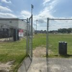 photo showing a fence and gate entrance to a grassy field