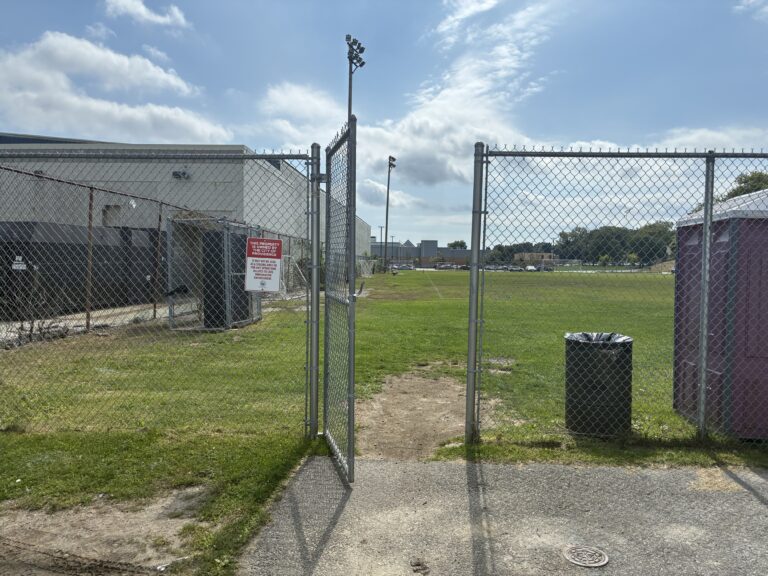 photo showing a fence and gate entrance to a grassy field