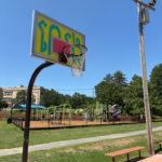 photo of a basketball net with playground structures in the background