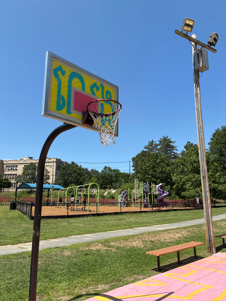 photo of a basketball net with playground structures in the background