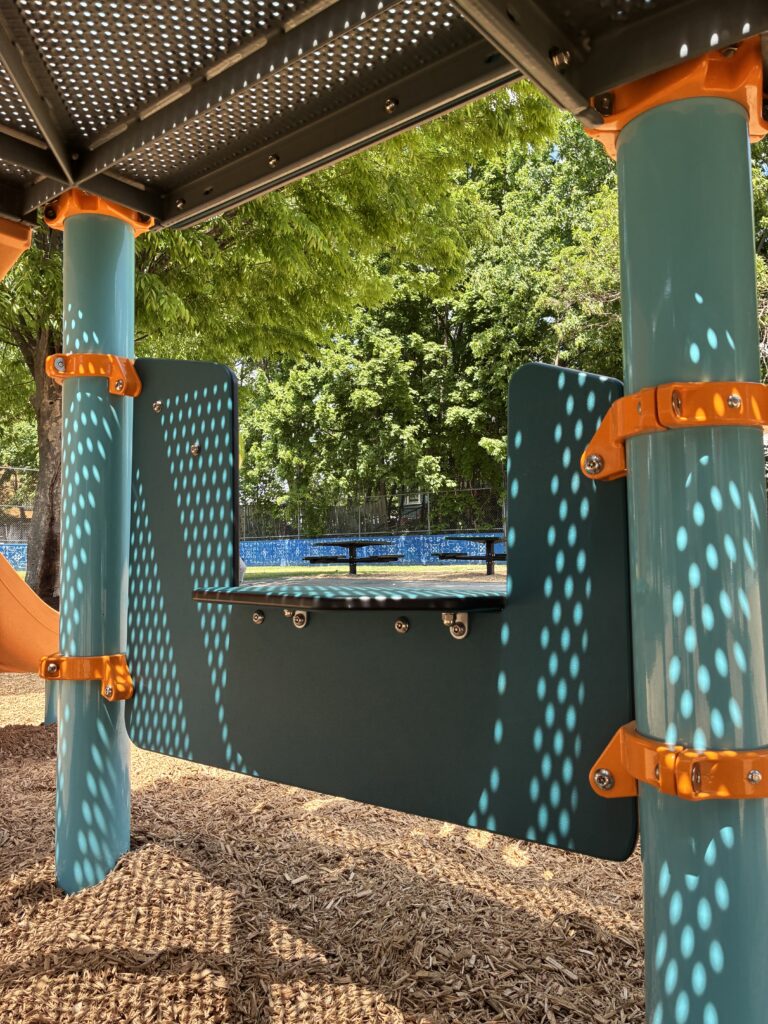 Pearl St Park looking at the picnic area from the storefront panel of the playground