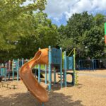 Pearl St Park entrance sign play structure for ages 5-12 and swings