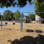 Pearl St Park swings for ages 2-12 looking south to the play structure