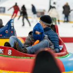 An adult and a child ride in an Ice Bumper Car at the Providence RInk