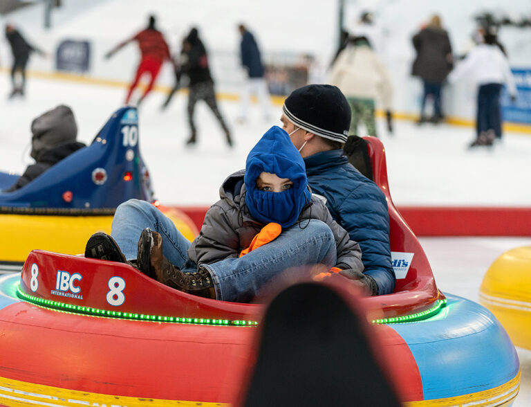 An adult and a child ride in an Ice Bumper Car at the Providence RInk