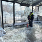 photo showing 2 workers that had recently cleared the snow out of a bus stop