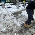 photo of someone shoveling snow on a sidewalk
