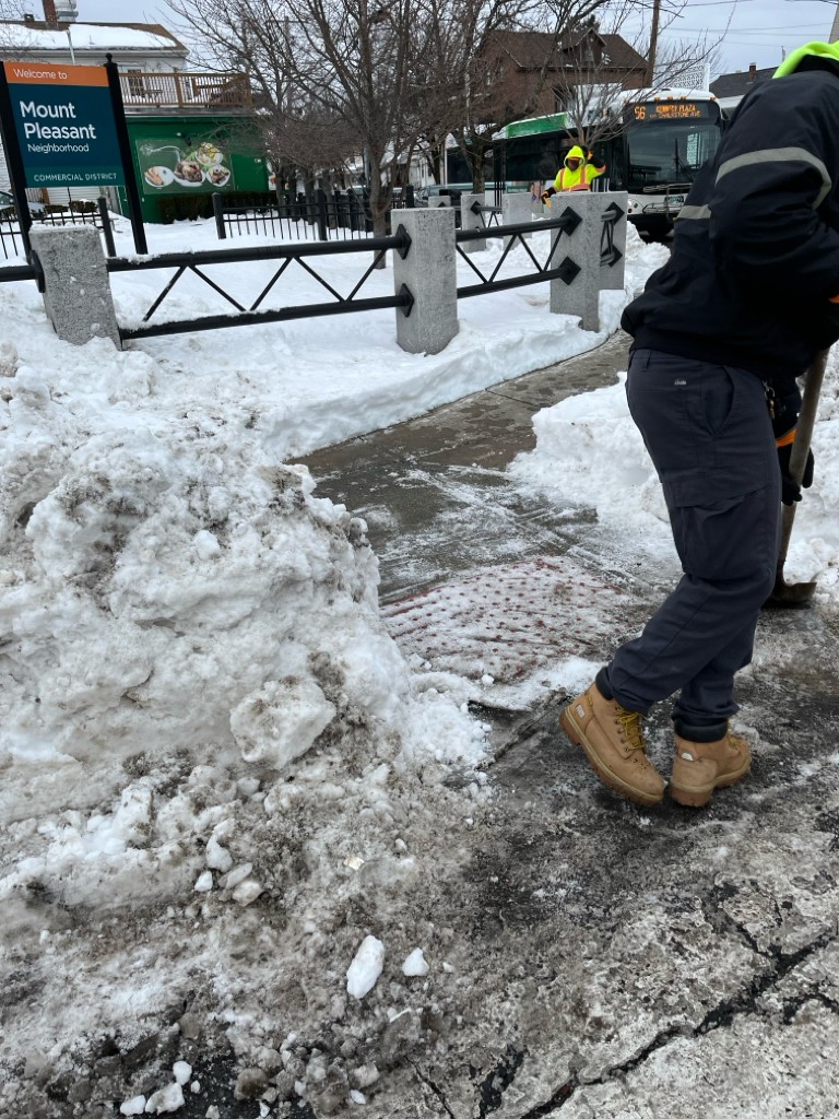 photo of someone shoveling snow on a sidewalk