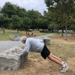 Photo of a person doing a push up on a large stone boulder