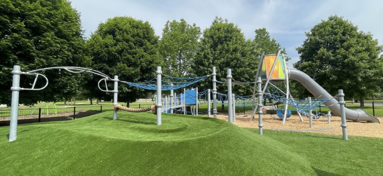 Neutaconkanut play structure for ages 5-12 wide view showing berm and varied terrain