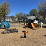 Father Lennon Park playground for ages 2-5 with spring rockers, balance feature, playhouse with slide, and climbing dome