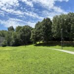 Father Lennon Park open field with lit paved walking path facing the Rec Center
