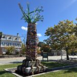 “The Storytelling AncesTree” sculptural installation at Columbus Square facing Elmwood Neighborhood sign