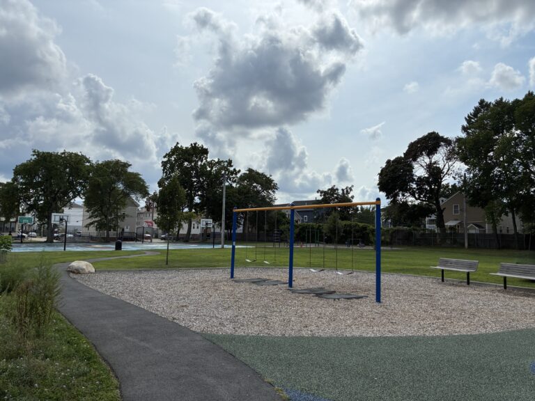 Harriet & Sayles Park paved walking path connects park amenities and entrances on Oxford, Harriet, and Sayles Streets, here running alongside a swing set for ages 5-12