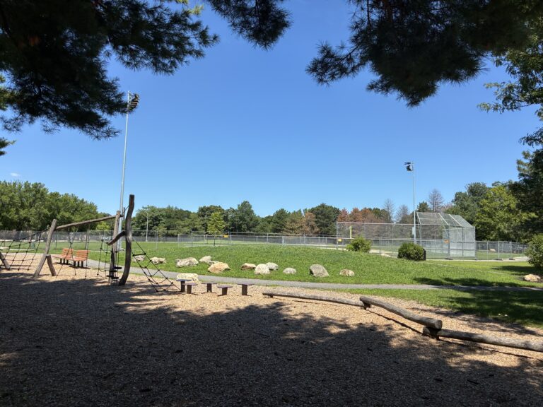 Iola French Park playground equipment for ages 5-12 includes an obstacle course. A grass berm separates the playground from the new ballfield and offers seating for both
