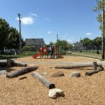 Joslin Park playground features natural play areas made of logs and boulders in addition to conventional metal and plastic composite play structures
