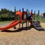 Joslin Park separate playground area for ages 2-5 with view of Olneyville skyline. That is a community garden behind the playground