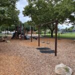 Joslin Park playground swings for ages 2-12 with futsal in the background