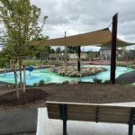 Joslin Park splashpad with multiple seating areas, shade structures, and plantings