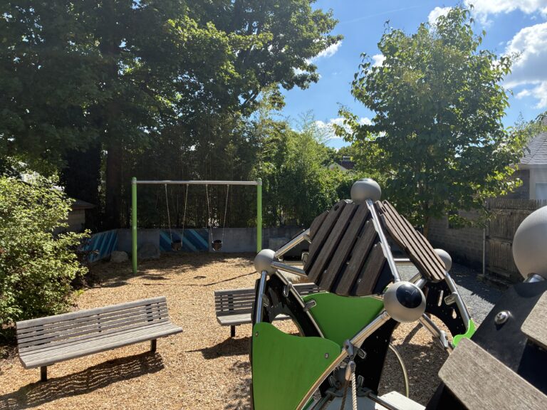 Morris Ave Park features playground bucket swings for ages 2-5, park benches, and a unique climbing structure