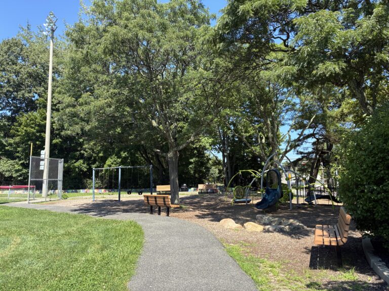Mt Pleasant Little League Park entrance to the playground with ample bench seating along a paved walkway