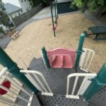 Pleasant St Park view from the top of the play structure to the double slide and picnic table