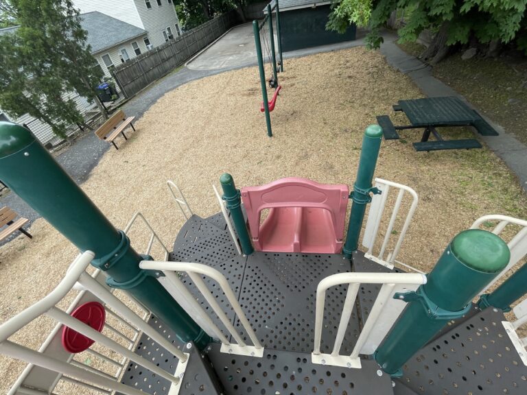 Pleasant St Park view from the top of the play structure to the double slide and picnic table