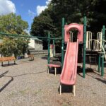 Pleasant St Park features park benches and play equipment for ages 2-12