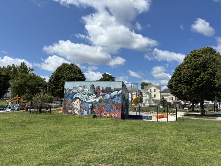 Richardson Park grassy area behind Al Carrington waterpark with mural on building