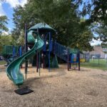 Sessions Street Park play structure for ages 5-12 features a unique curved slide, two activity panels, and central climbing tower