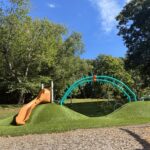 Viscolosi Park play features for ages 5-12 include a curved embankment slide, arch climber, cargo net, and synthetic turf berm with obstacles